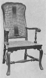 A reproduction of a walnut chair with cane seat and back, of the William and Mary period.