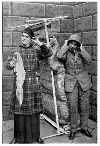 A man and woman dress in each other's clothing in a brick room.