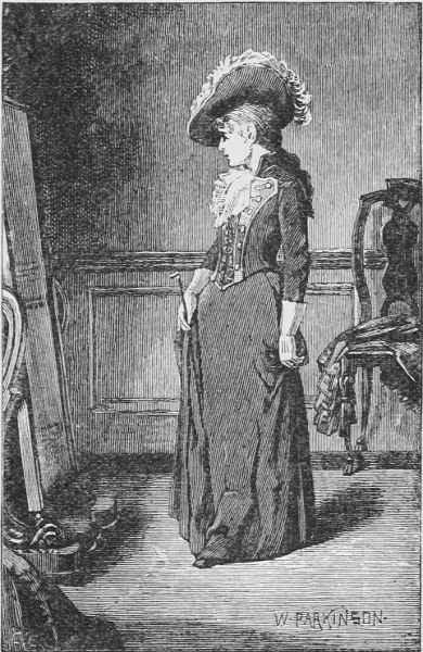 Lady in hat and dress looking at herself in mirror.