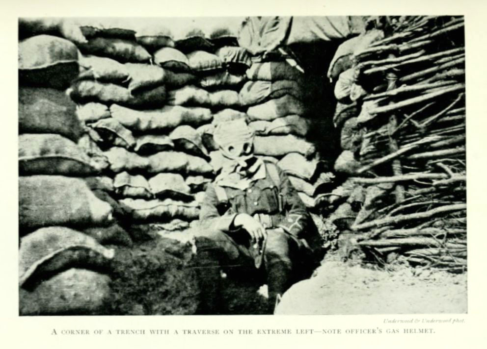 A corner of a trench with a traverse in the extreme left—note officer’s gas helmet.