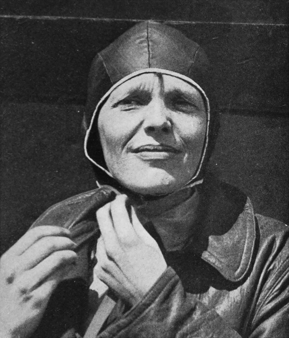 Photo closeup of Earhart strapping on a leather helmet