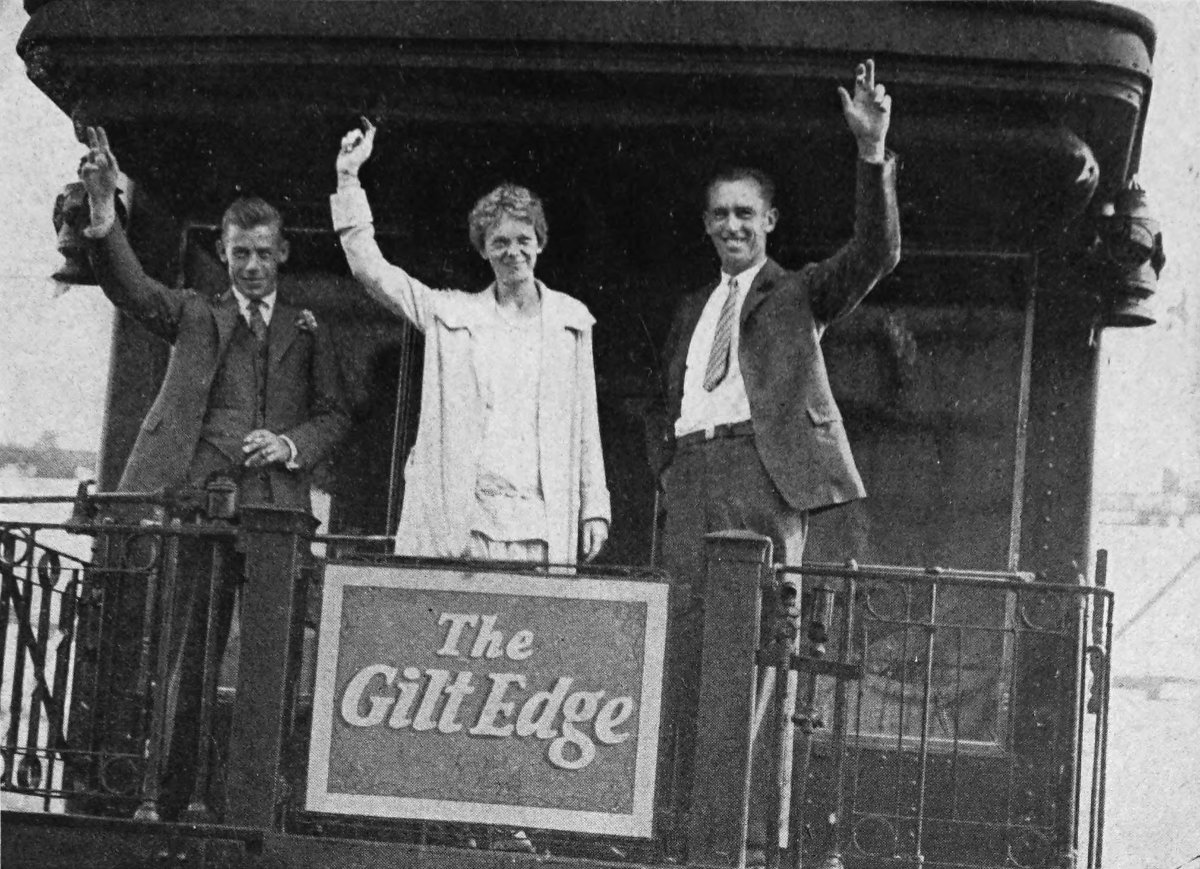 Photo wide outdoor shot of Friendship waving from rear platform rail car; a sign saying “The Gilt Edge”                 hangs on railing