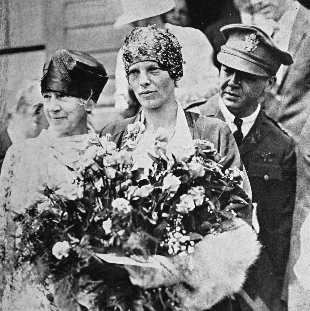 Photo medium shot outdoor of Earhart’s mother, Earhart, and Woolley; Earhart is holding large bouquet of flowers