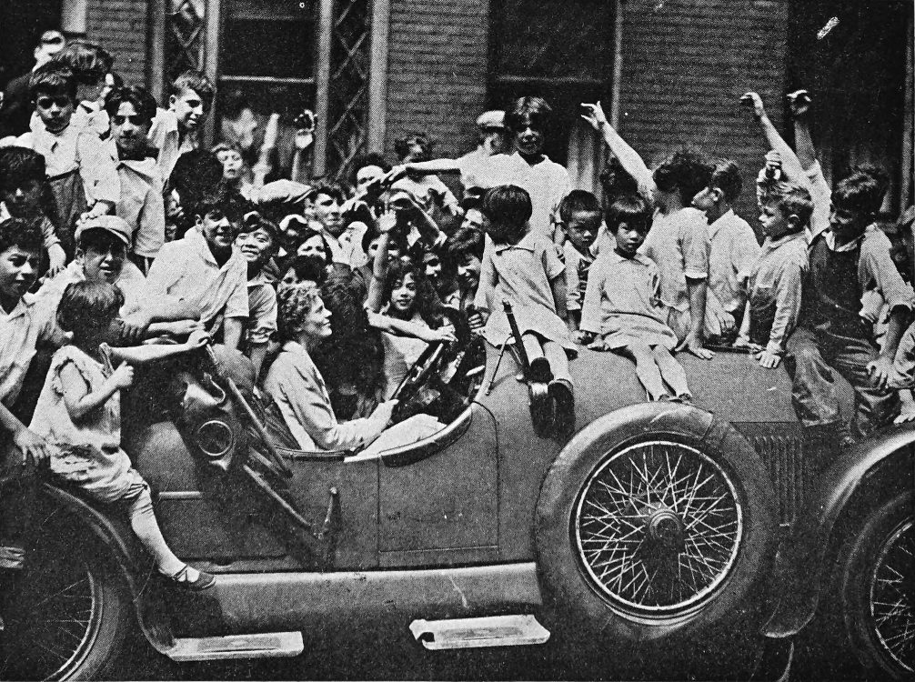 Photo wide profile shot outdoor of Earhart in car swarmed by children
