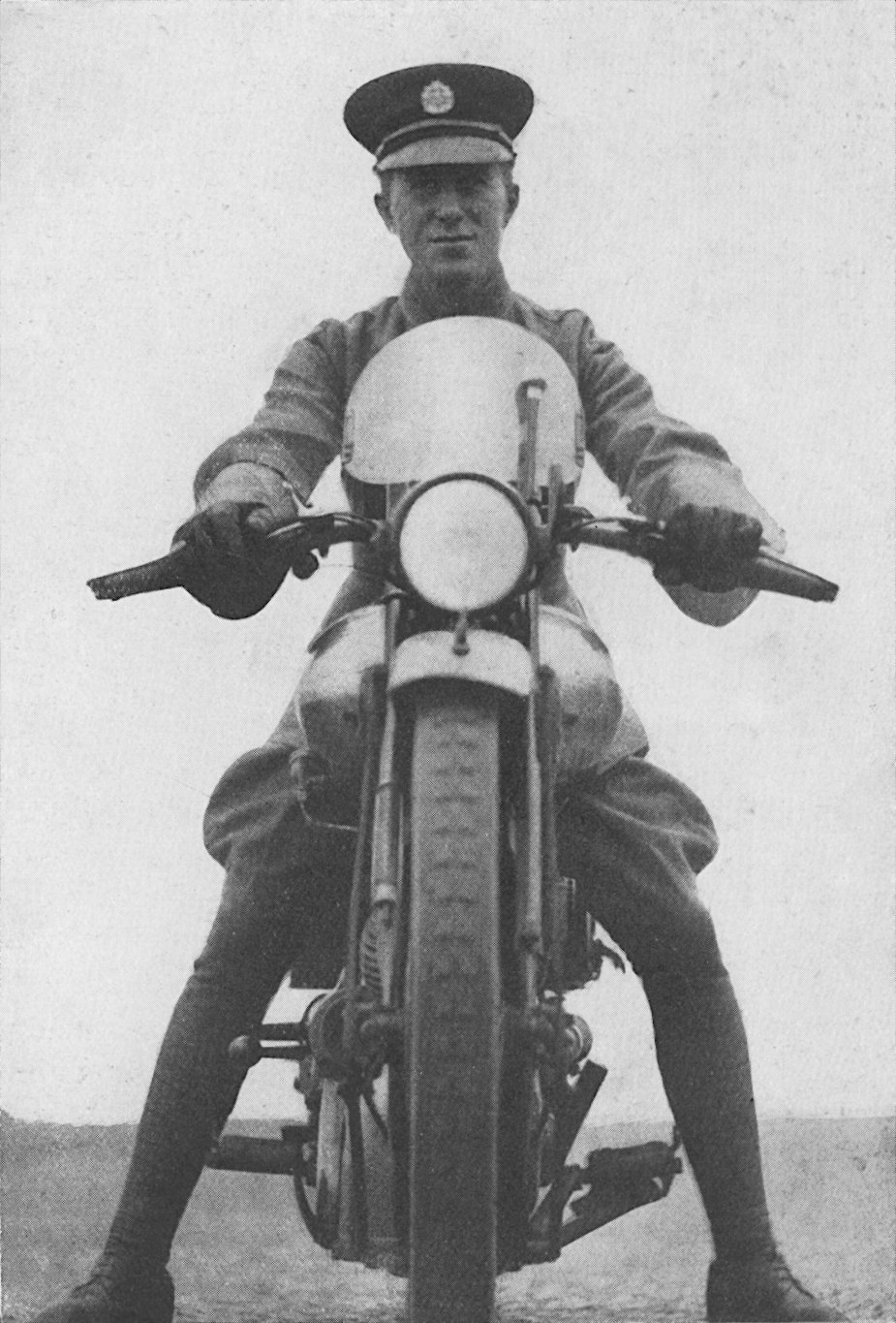 Photo low full front shot looking up at Lawrence astride a stationary motor-bicycle