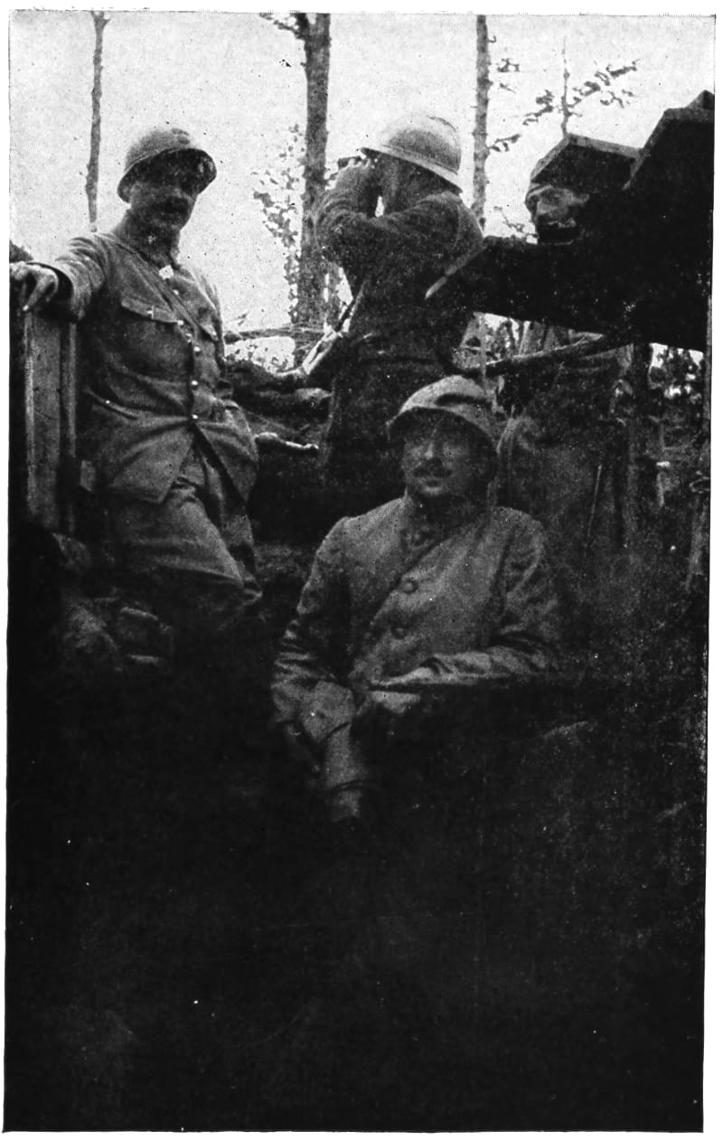 Three soldiers in a trench while a fourth uses binoculars.