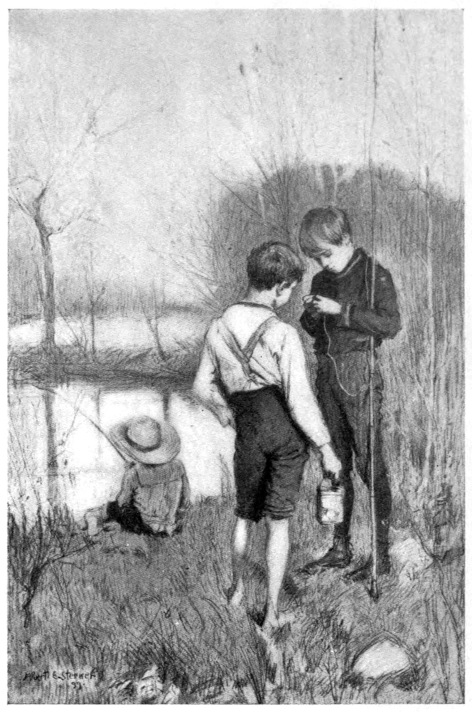 Two boys, standing, put on a lure to a fishing line. A third boy, back to viewer, is fishing in the pond beyond.