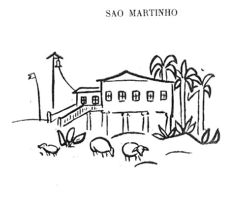 Edifício de fazenda com sino e bandeira ao lado, cercado por palmeiras e arbustos, com animais pastando em frente.