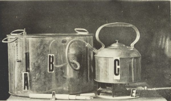 Photograph of large still attached to what looks like a tea kettle on a burner