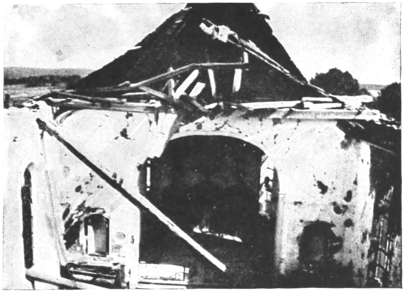 A building with a damaged roof with debris nearby.