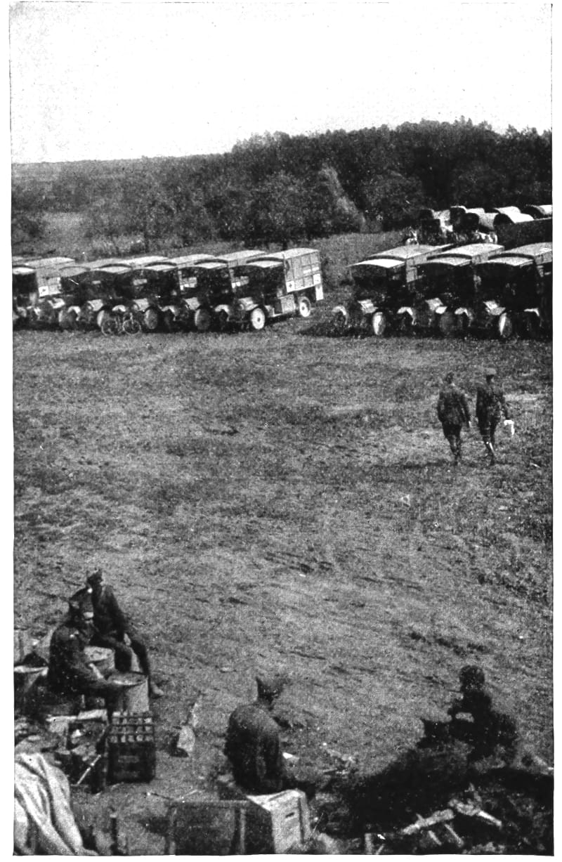 A row of trucks a few yards away from some uniformed men sitting.