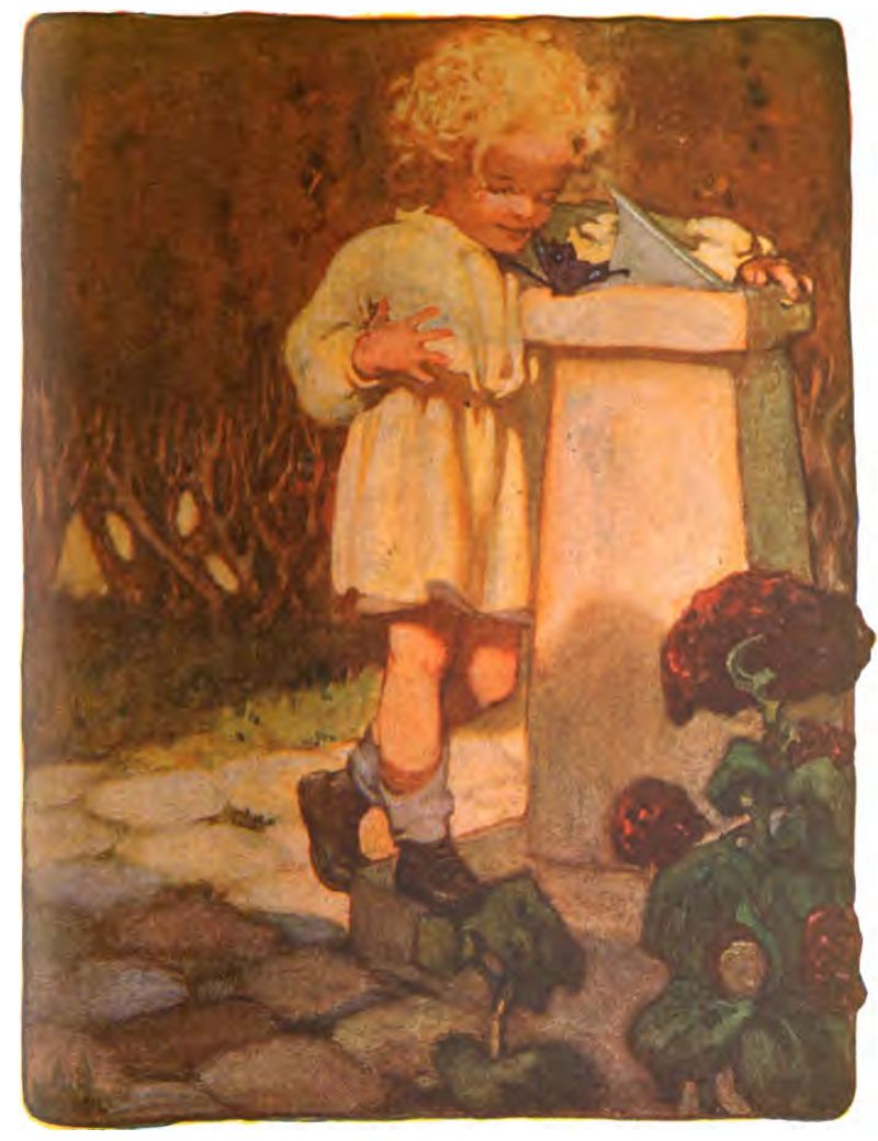 A young child with blonde curly hair stands on a stone path, surrounded by flowers and shrubs.
The child wears a light tunic or smock dress, dark shoes, and rolled socks.
They look closely at a dark butterfly resting on a stone pedestal with a sundial.
